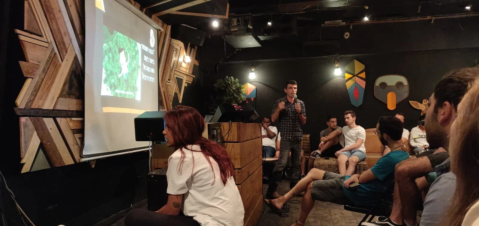 Dani leading a talk beside a projection screen in an intimate venue